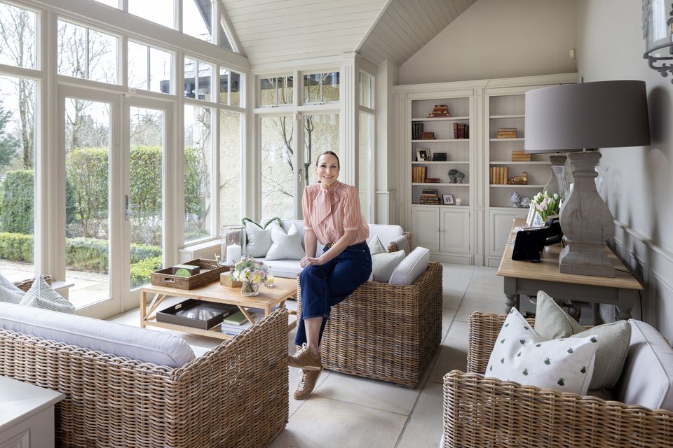 Stylist Jess Colivet in the conservatory of her stunning home in Kildare. This sunny space was added ten years ago and the many windows afford wonderful views of the grounds. The floor is Italian stone and the rattan furniture is from Flamant. The side table and lamp are from Helen Turkington. Photo: Tony Gavin